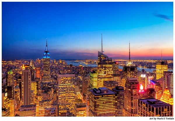 Golden city lights of the Manhattan Skyline Against dusk blue skies - Print by Mark Tisdale